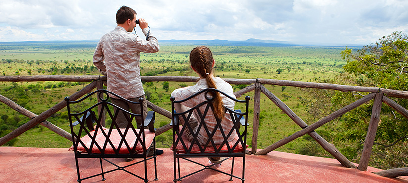 Young couple observing Tarangire National Park Tanzania Africa from lodge balcony